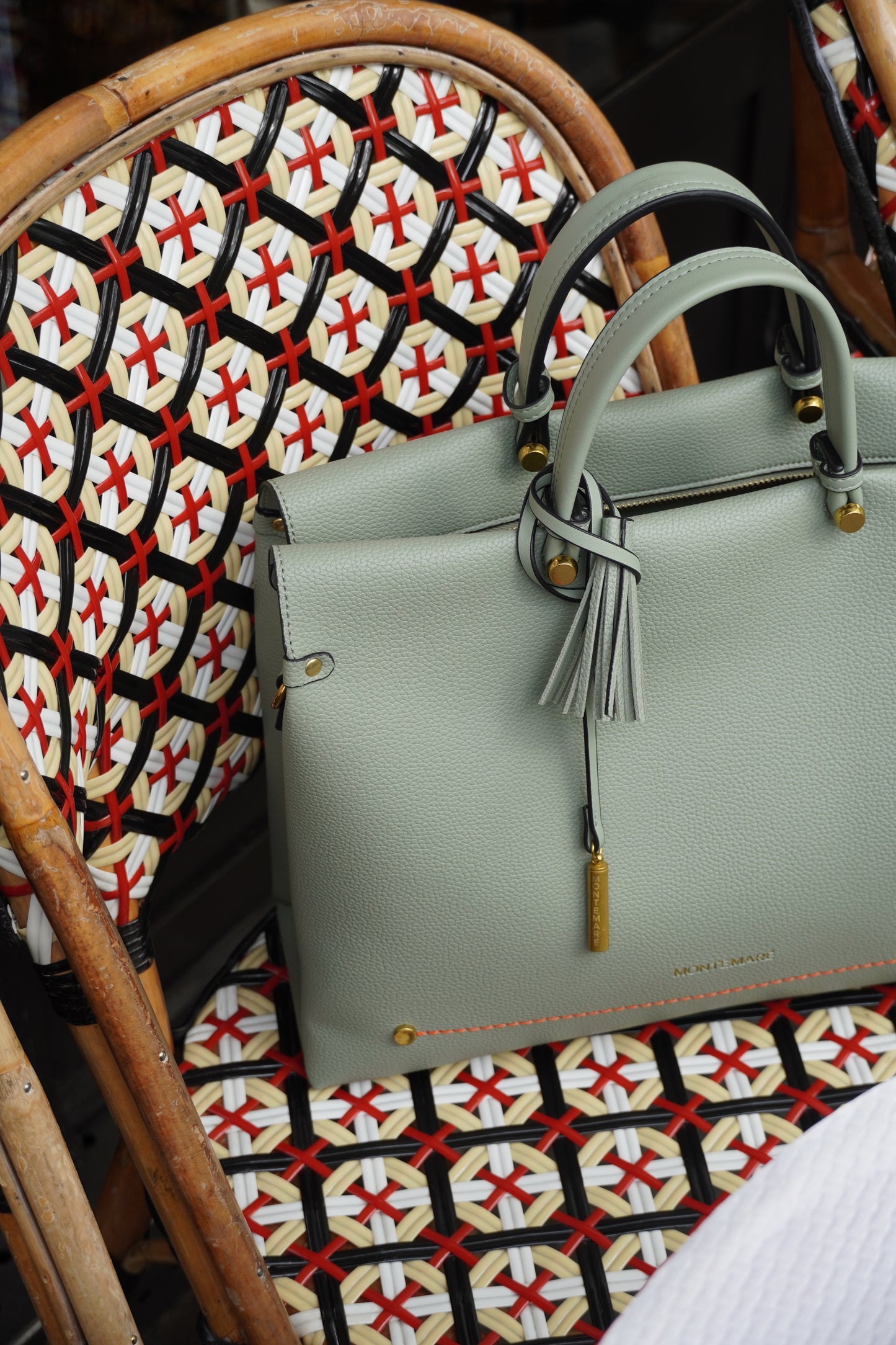 Light blue handbag with a tassel on a chair with a patterned cushion