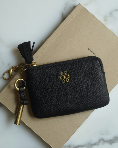 Montemaré black vegan leather RFID card case with gold hardware, keychain clip, and signature safety whistle tassel.