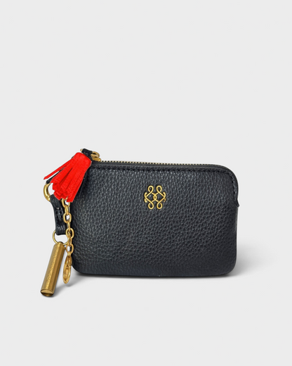 Montemaré black vegan leather RFID card case with a gold logo, zipper closure, and a red whistle tassel keychain.