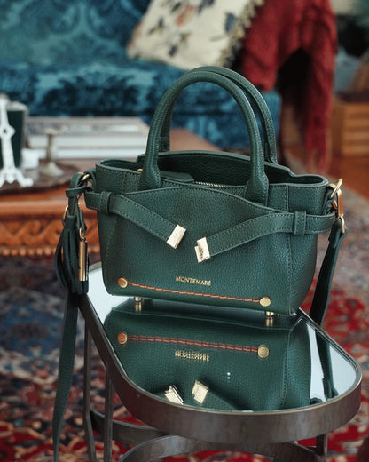 Montemaré Mayfair Mini Crossbody bag in dark green pebbled leather with gold hardware and decorative strap detail.