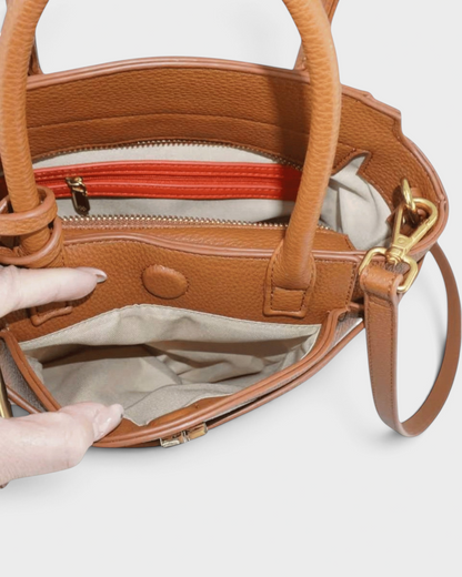 Interior view of a Montemaré Mayfair Tall Crossbody bag in tan pebbled leather with a bright orange zipper pocket.