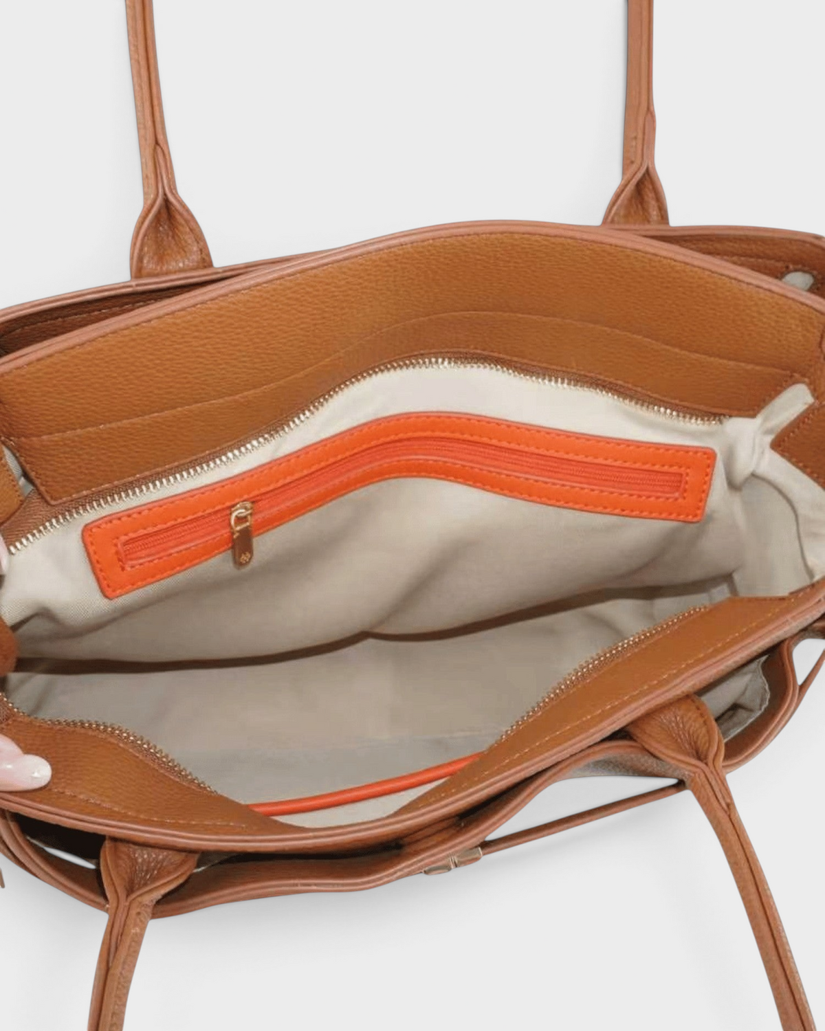 Interior view of a Montemaré Mayfair Work Tote in brown leather with a bright orange zippered pocket and beige lining.