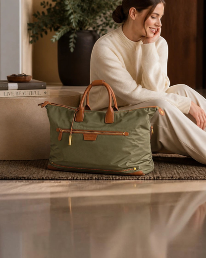 Montemaré olive green waterproof nylon weekender bag with brown leather trim and gold hardware held by a woman.