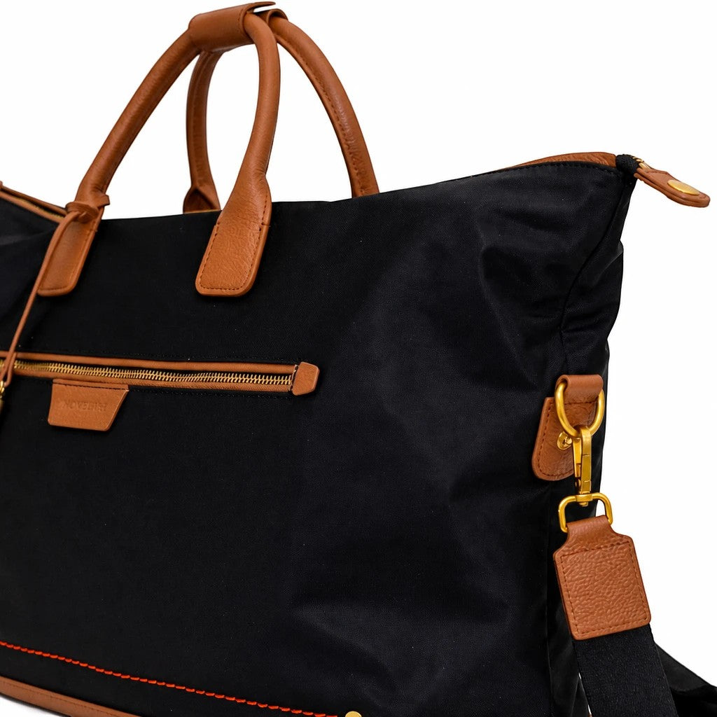 Montemaré Oslo Carry On weekender bag in black waterproof nylon with tan leather trim and gold hardware details.
