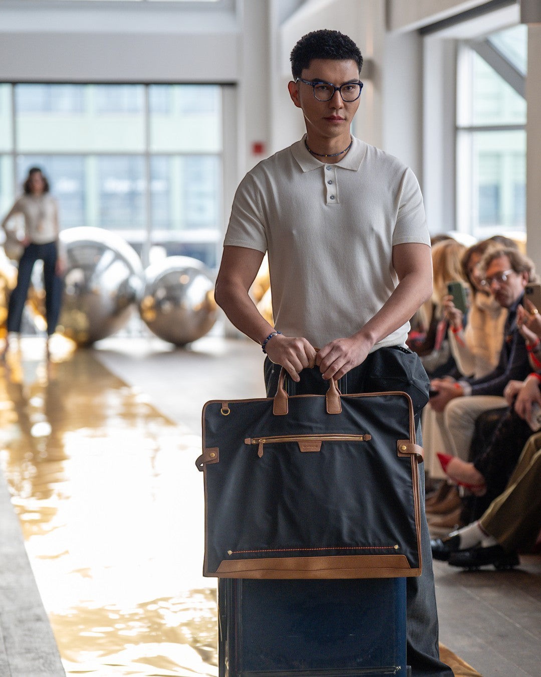 Montemaré Oslo garment bag in black waterproof nylon with leather trim held by a man on a fashion runway
