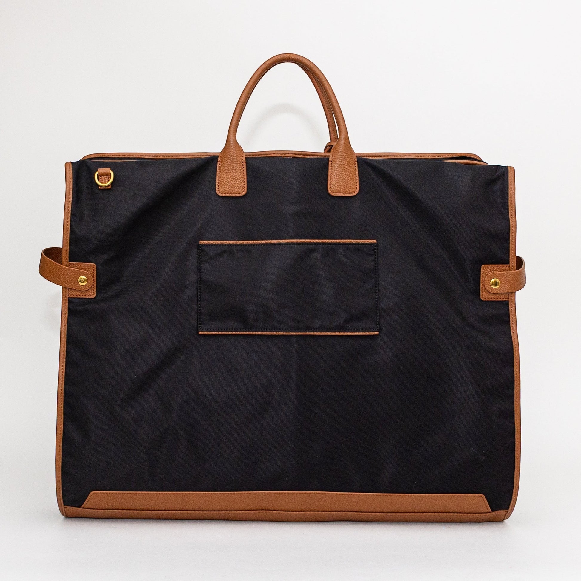 Montemaré Oslo garment bag in black waterproof nylon with tan leather trim, featuring top handles and side straps.