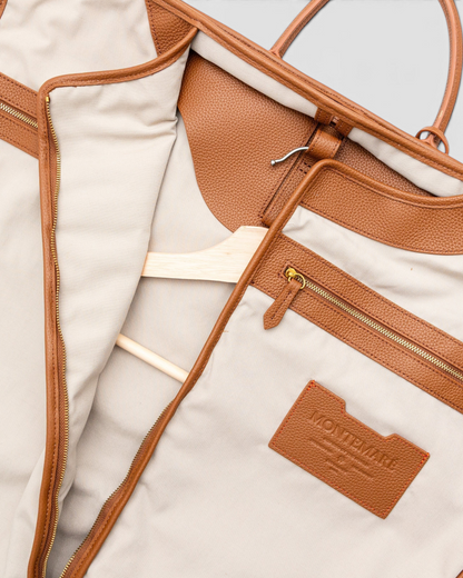 Interior view of a Montemaré Oslo garment bag featuring beige cotton lining, brown leather trim, and a wooden hanger.