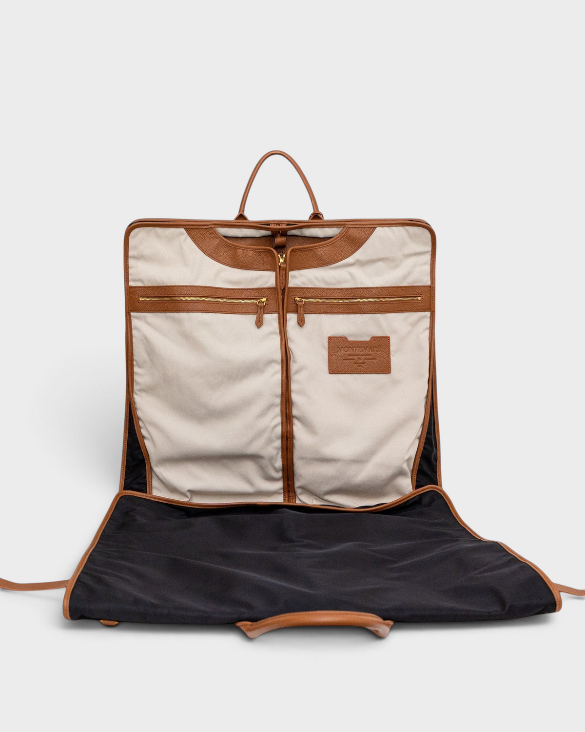 Montemaré Oslo tri-fold garment bag in beige and brown with leather trim, open to show interior storage compartments.