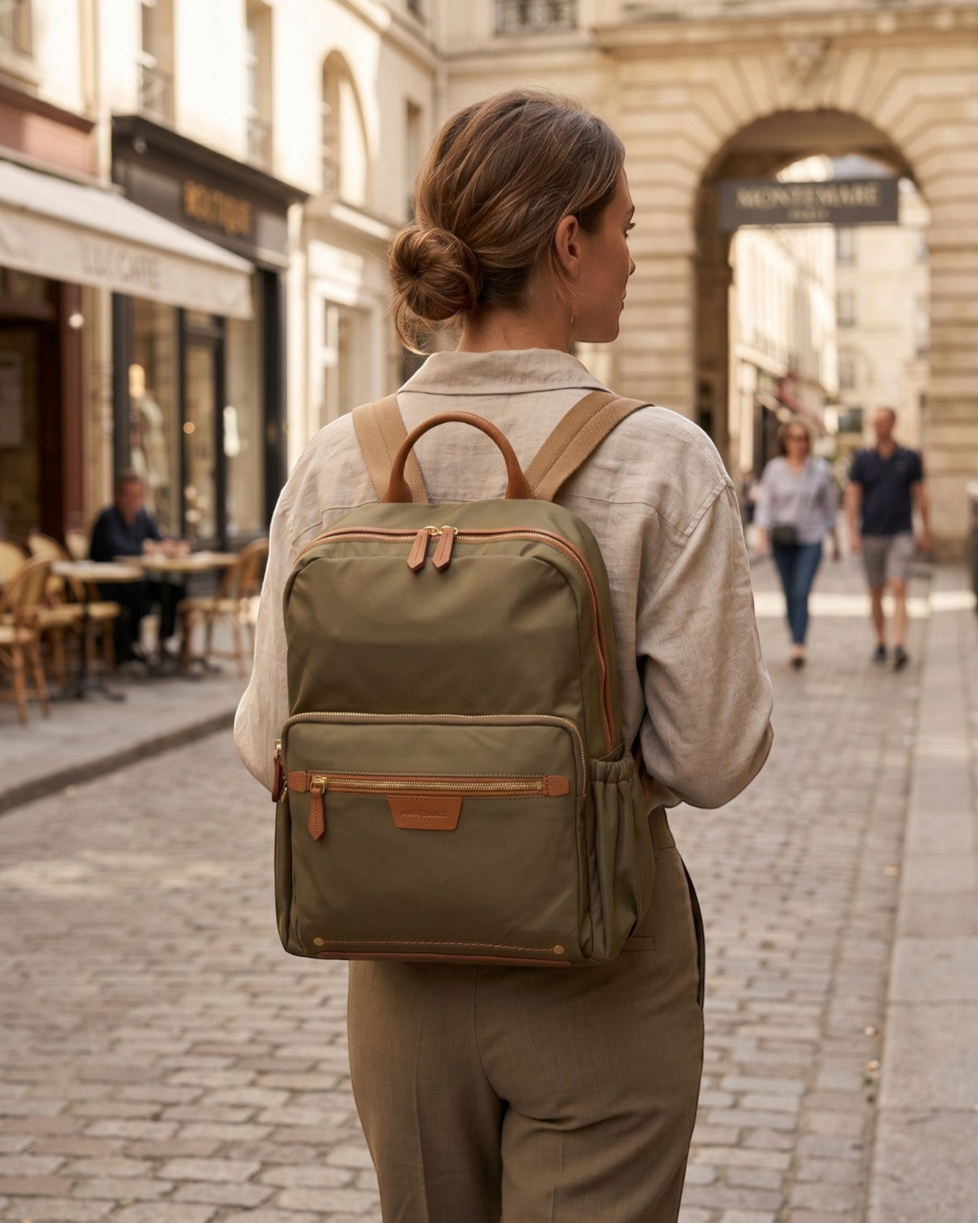 Montemaré Oslo olive green nylon and leather backpack worn by a woman walking on a cobblestone street in Paris