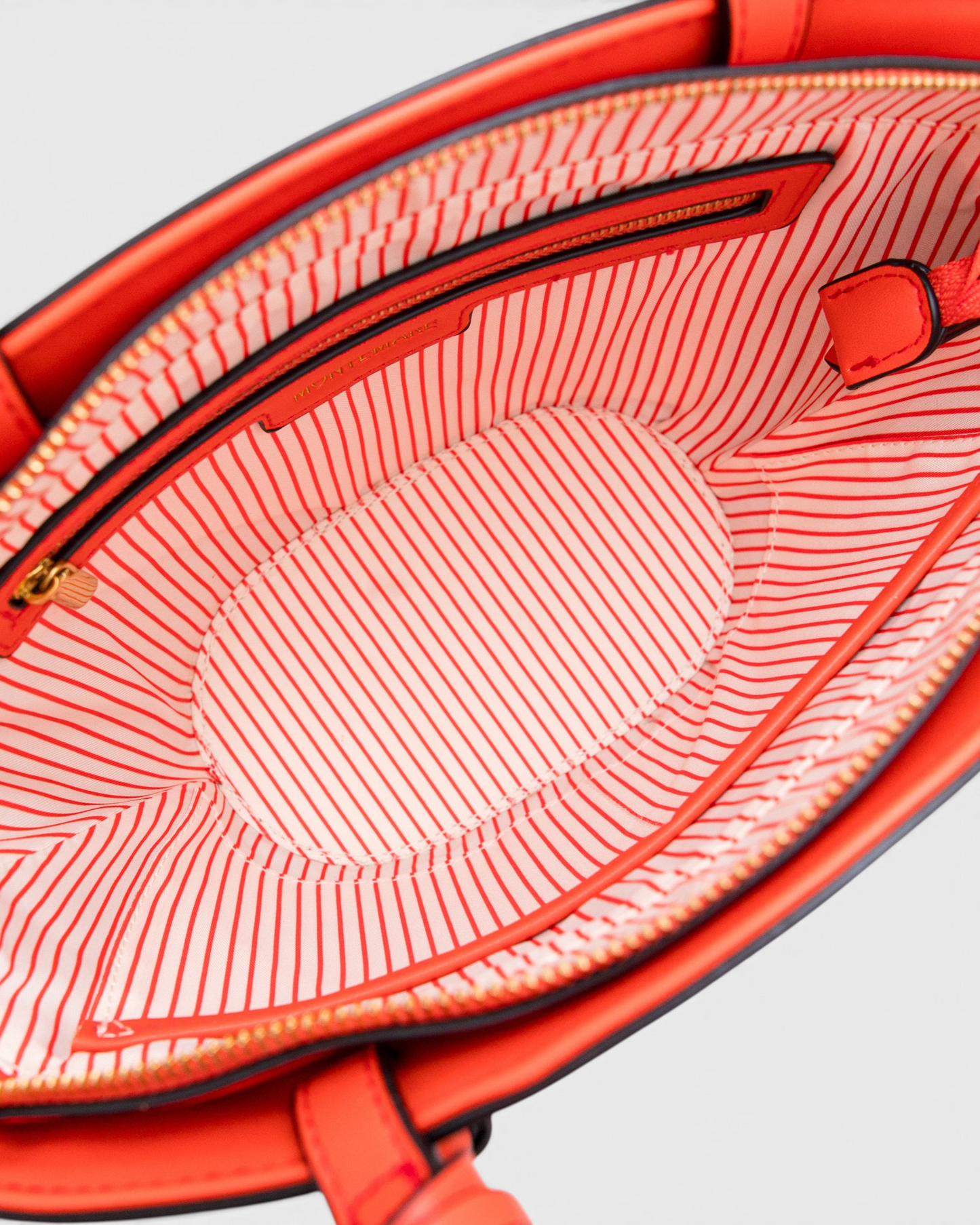 Interior of Montemaré Palma Crossbody bag featuring orange and white striped lining and a secure zip top closure.