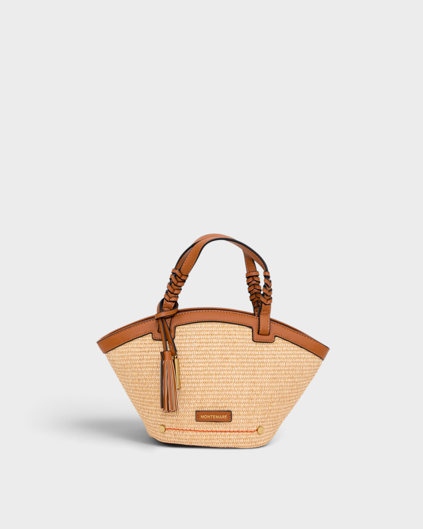 Montemaré Palma Crossbody bag in straw-like material with tan vegan leather trim, braided handles, and a tassel charm.