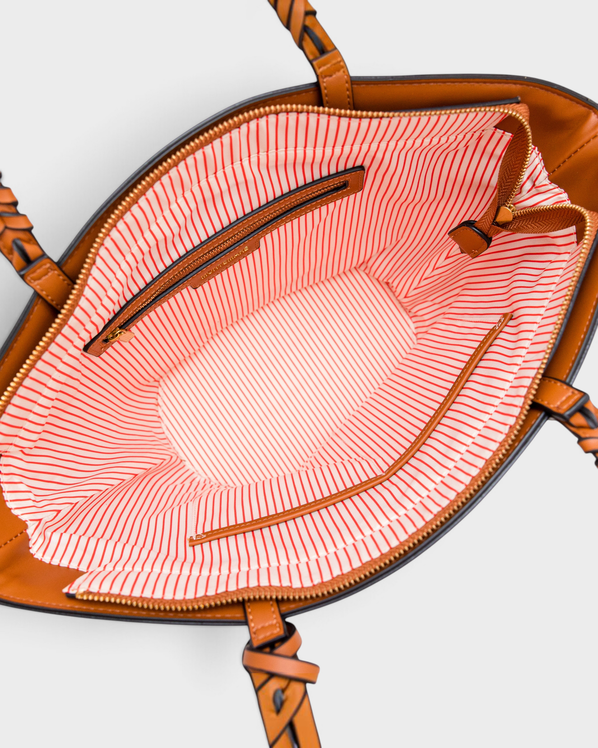 Interior view of Montemaré Palma Tote featuring orange and white striped lining, zip pocket, and brown vegan leather.