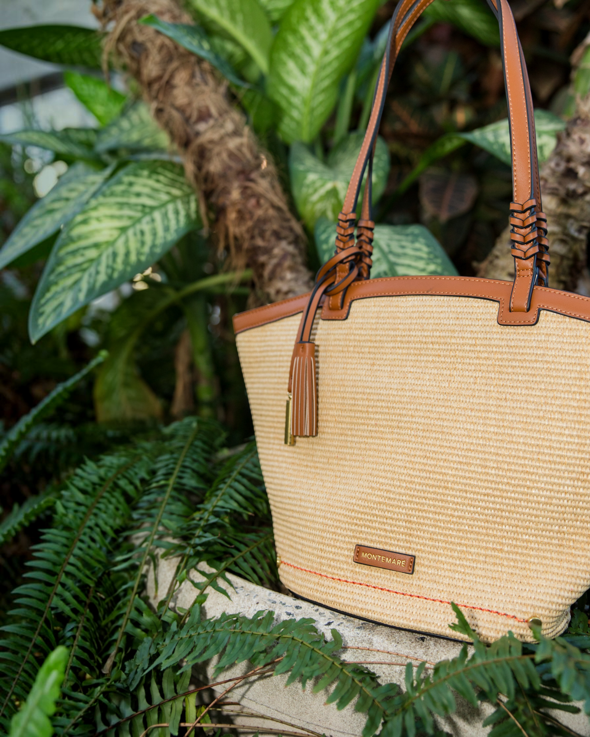 Montemaré Palma Tote in straw-like material with tan vegan leather trim and a signature safety whistle tassel.