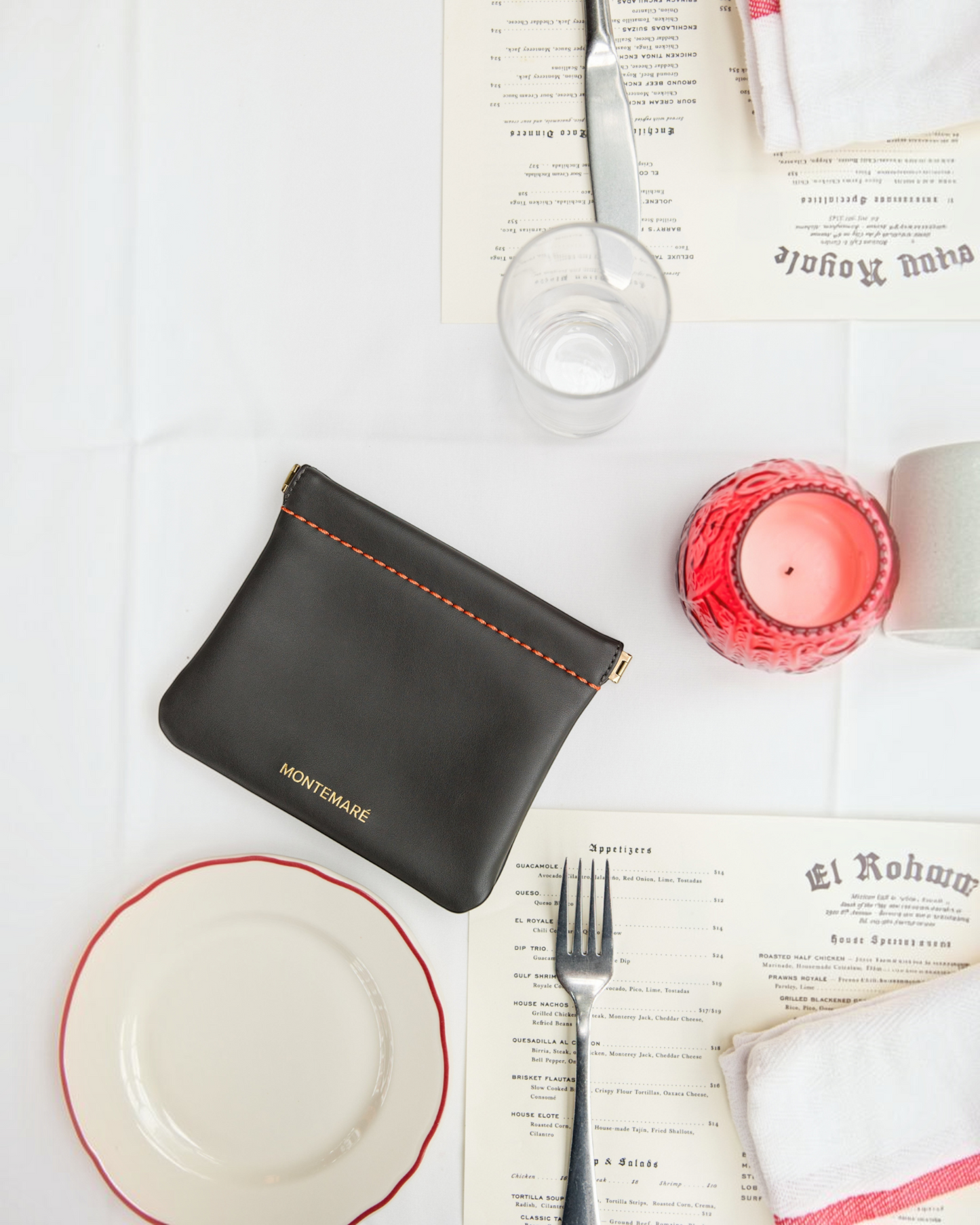 Montemaré Roma square pouch in black vegan leather with orange stitching, featuring a secure spring-frame closure.