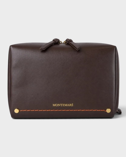Montemaré Roma standing toiletry case in dark brown vegan leather with orange contrast stitching and gold hardware.