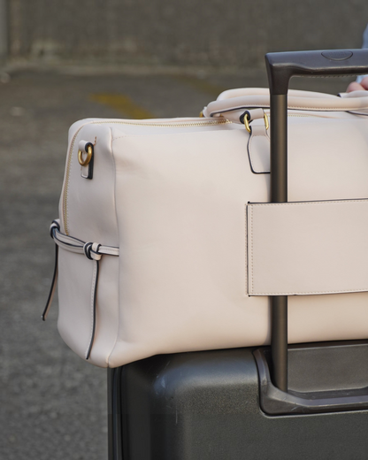 Montemaré Roma Duffel in beige vegan leather attached to a rolling suitcase handle via its integrated trolley sleeve