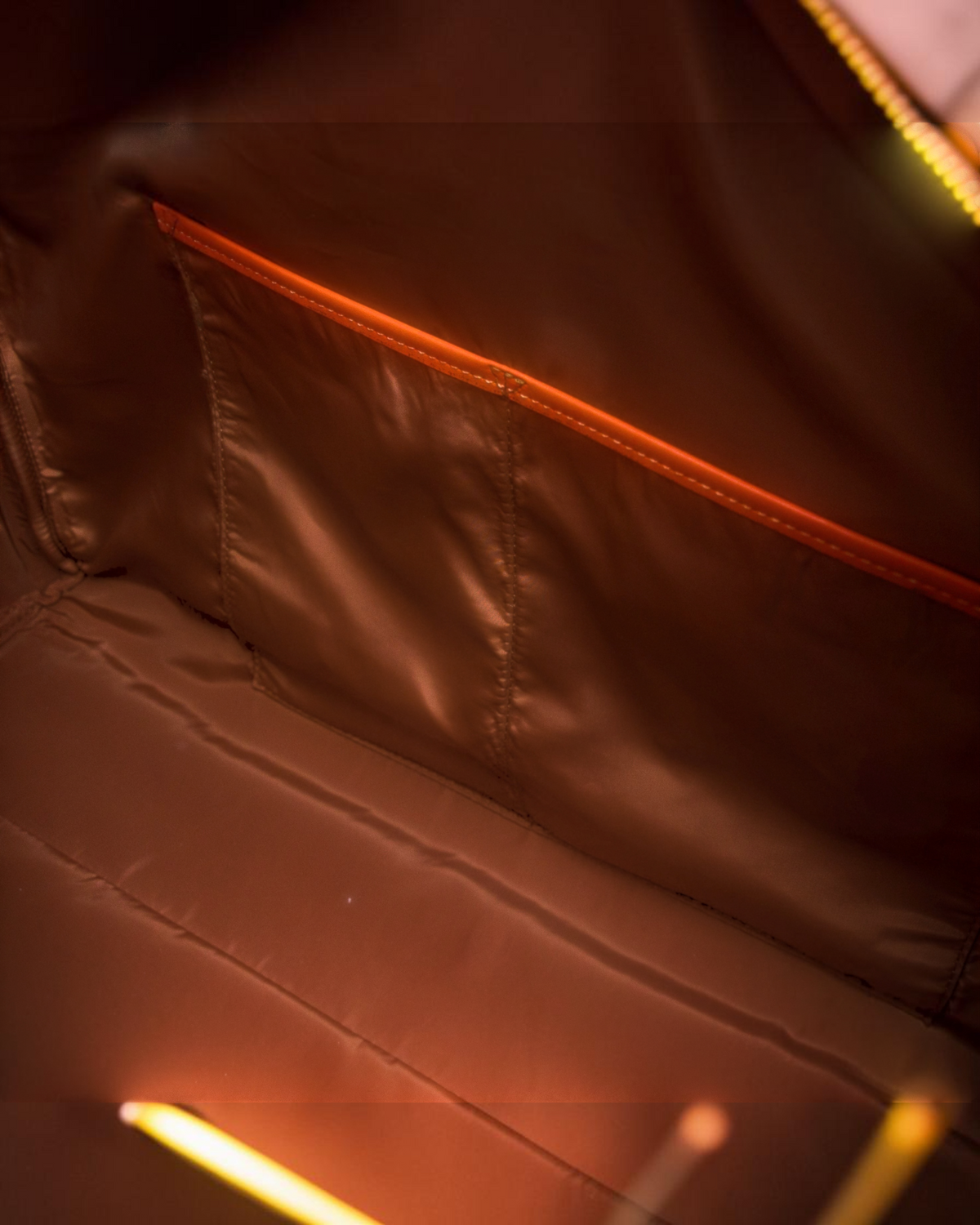 Interior of Montemaré Roma Duffel featuring brown water-resistant lining and vibrant orange pocket trim detail.