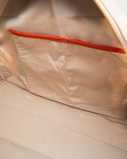 Interior of Montemaré Roma Duffel featuring beige water-resistant lining and a pocket with vibrant orange trim.