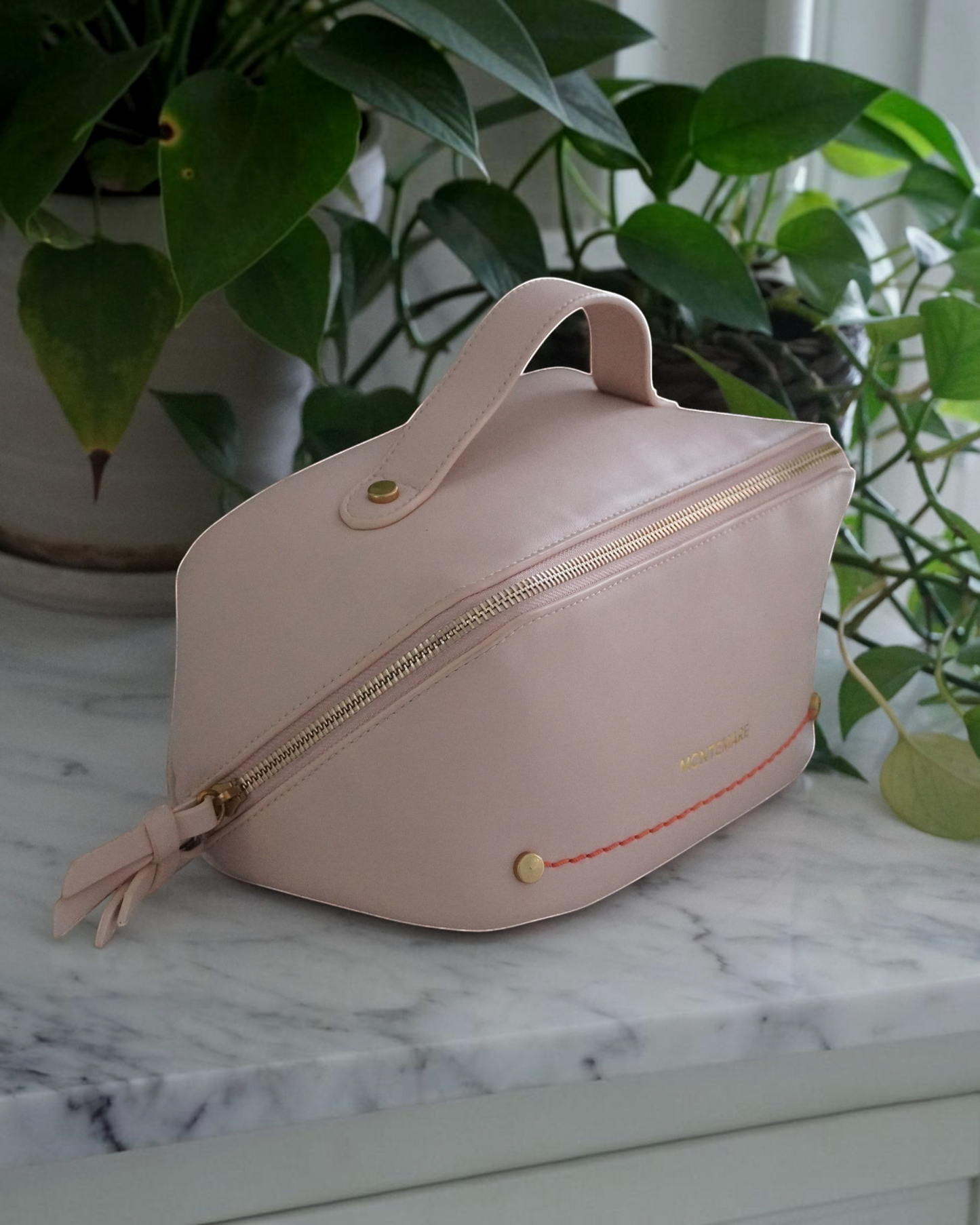 Montemaré Roma foldout toiletry case in blush vegan leather with gold zipper and orange accent stitching