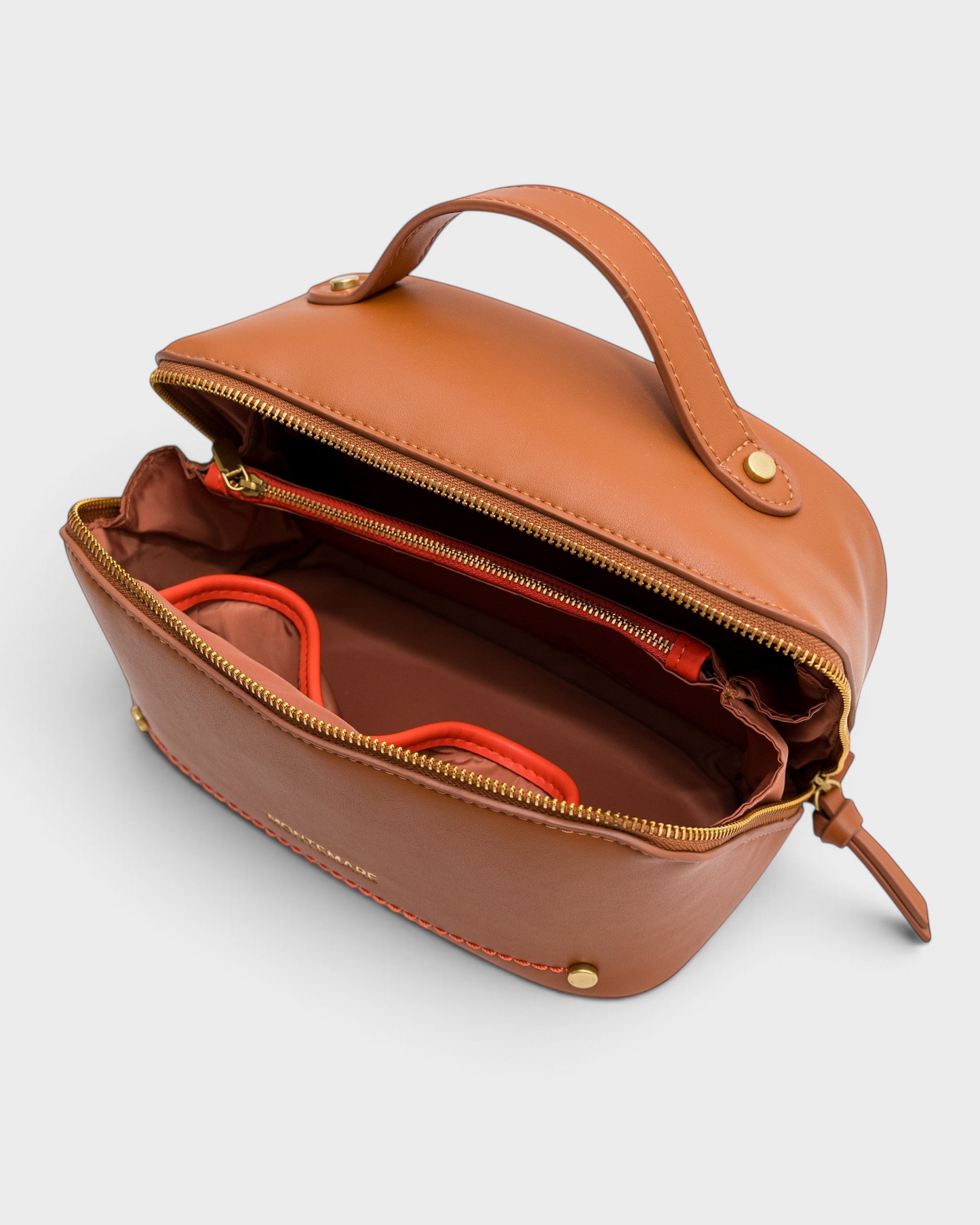Montemaré Roma foldout toiletry case in tan vegan leather with orange accents, top handle, and wide zippered opening.
