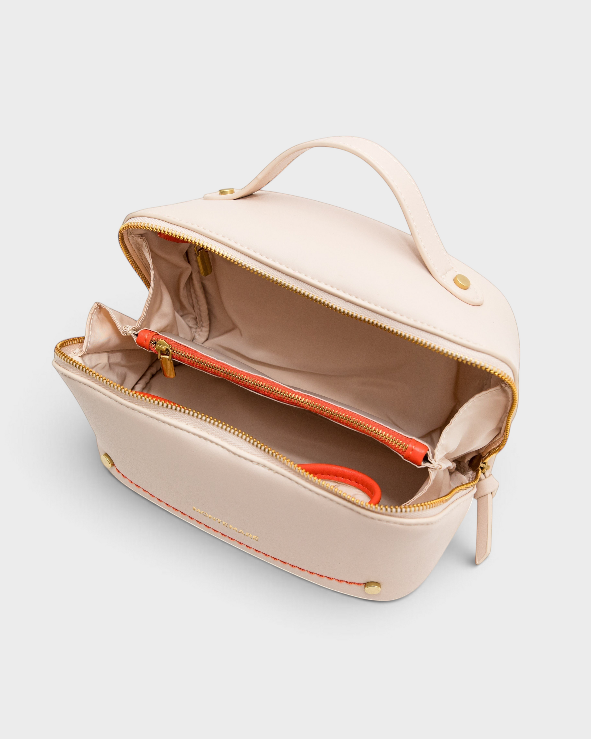 Montemaré Roma foldout toiletry case in cream vegan leather with orange accents, top handle, and wide zippered opening.
