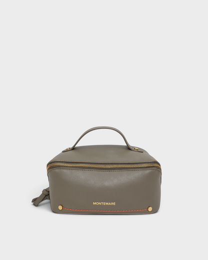 Montemaré Roma foldout toiletry case in grey vegan leather with orange stitching and a top handle on a neutral background