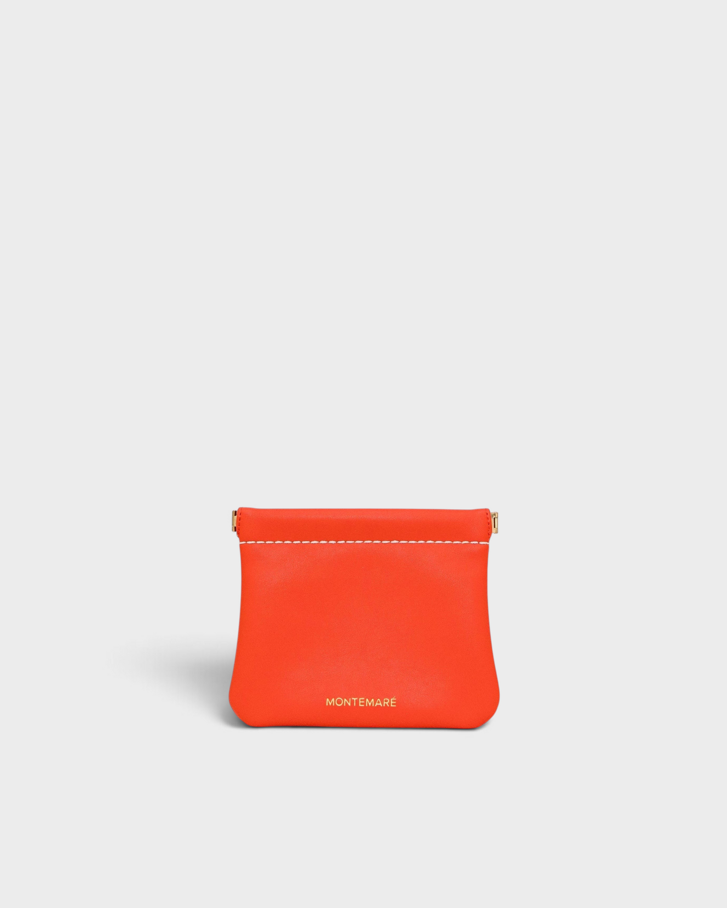 Montemaré Roma square pouch in vibrant orange vegan leather with a secure spring-frame closure and gold logo detail.