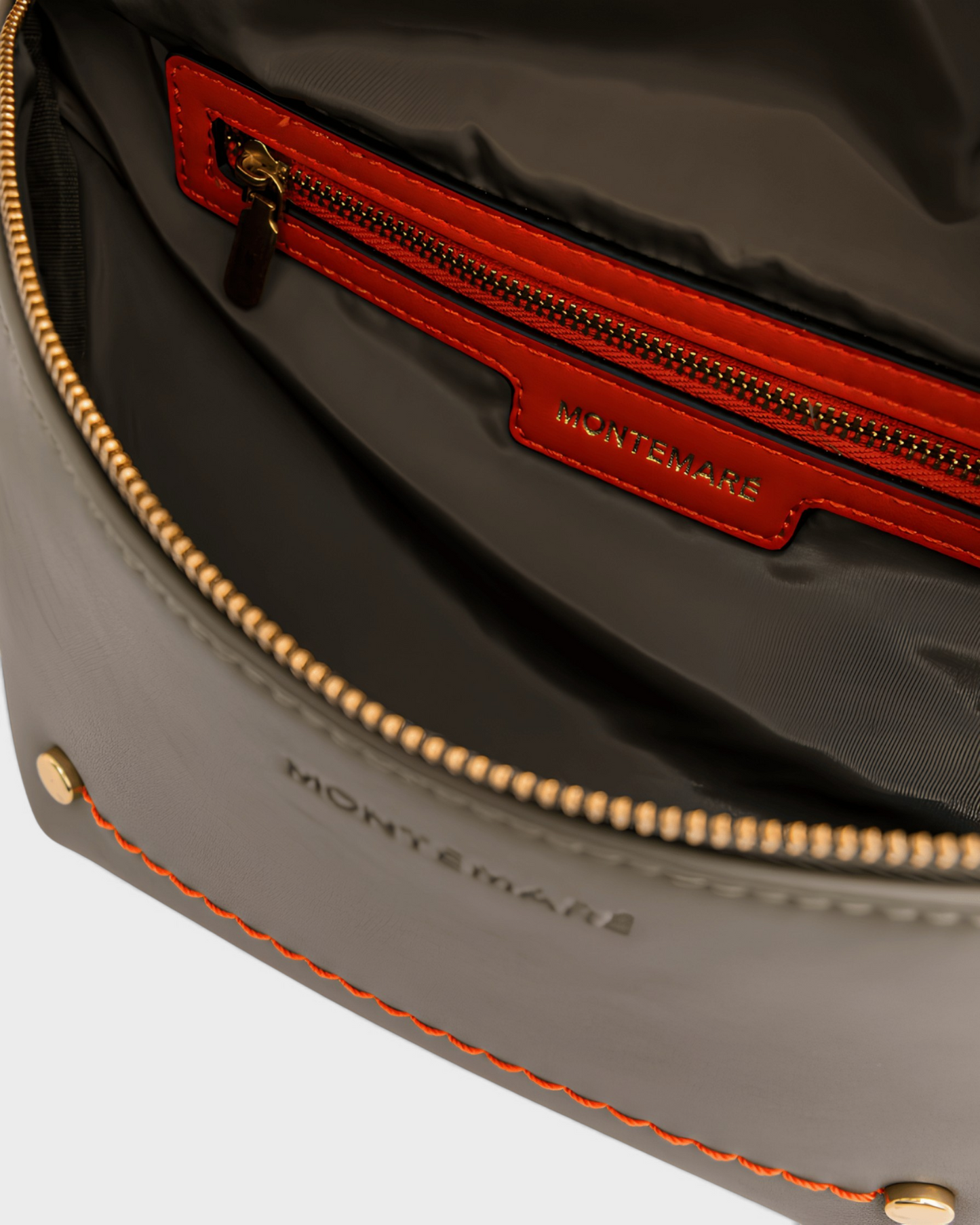 Interior view of the Montemaré Roma Sling bag featuring grey vegan leather, orange trim, and a secure zip pocket.