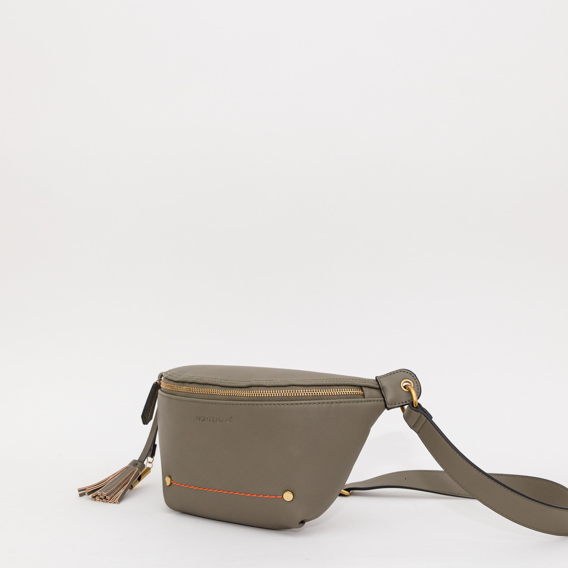 Green sling with bright orange stitching, brass-finished zipper and whistle tassel angled on a white background.