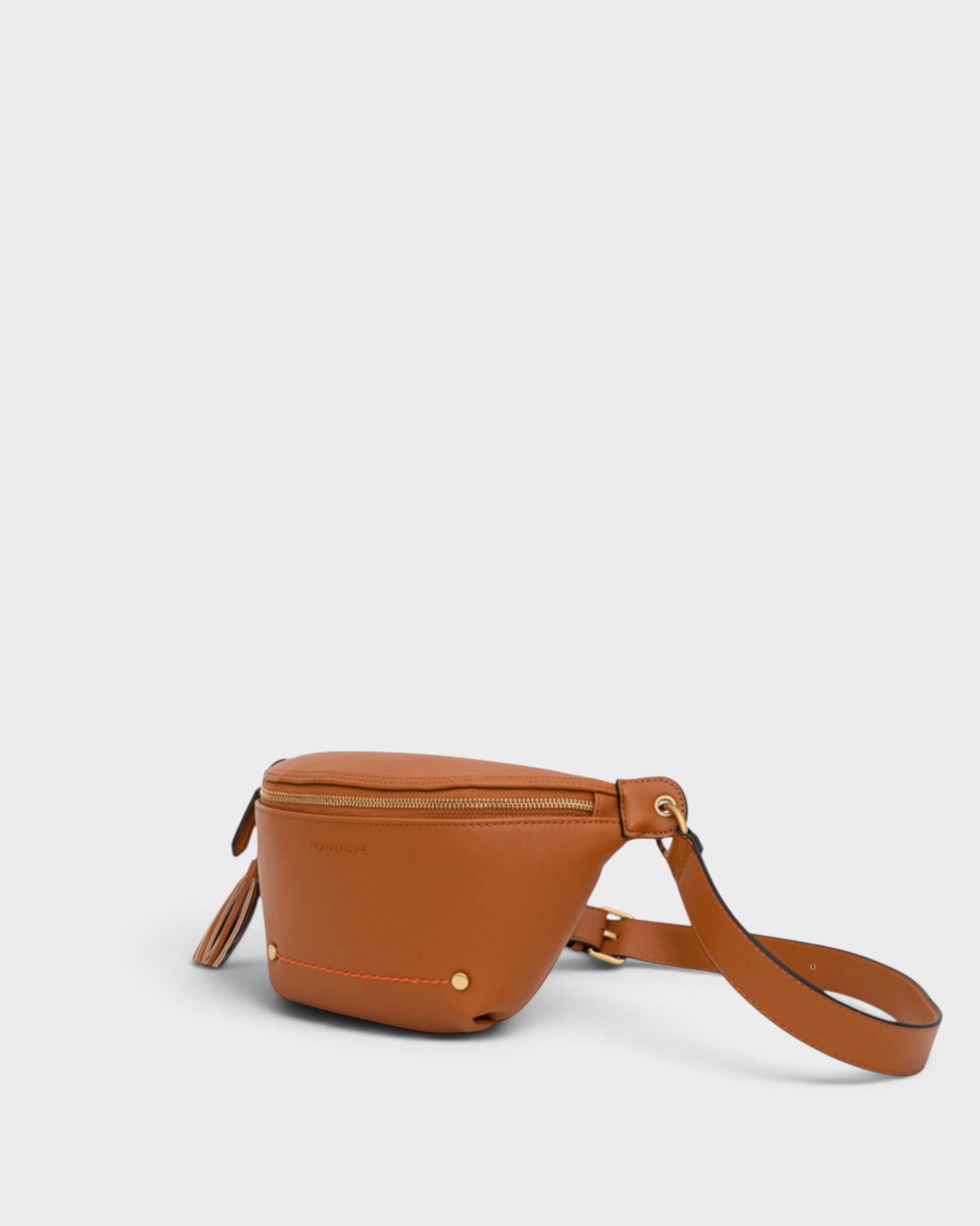 Montemaré Roma Sling bag in tan vegan leather with gold hardware, zip pockets, and a signature safety whistle tassel.