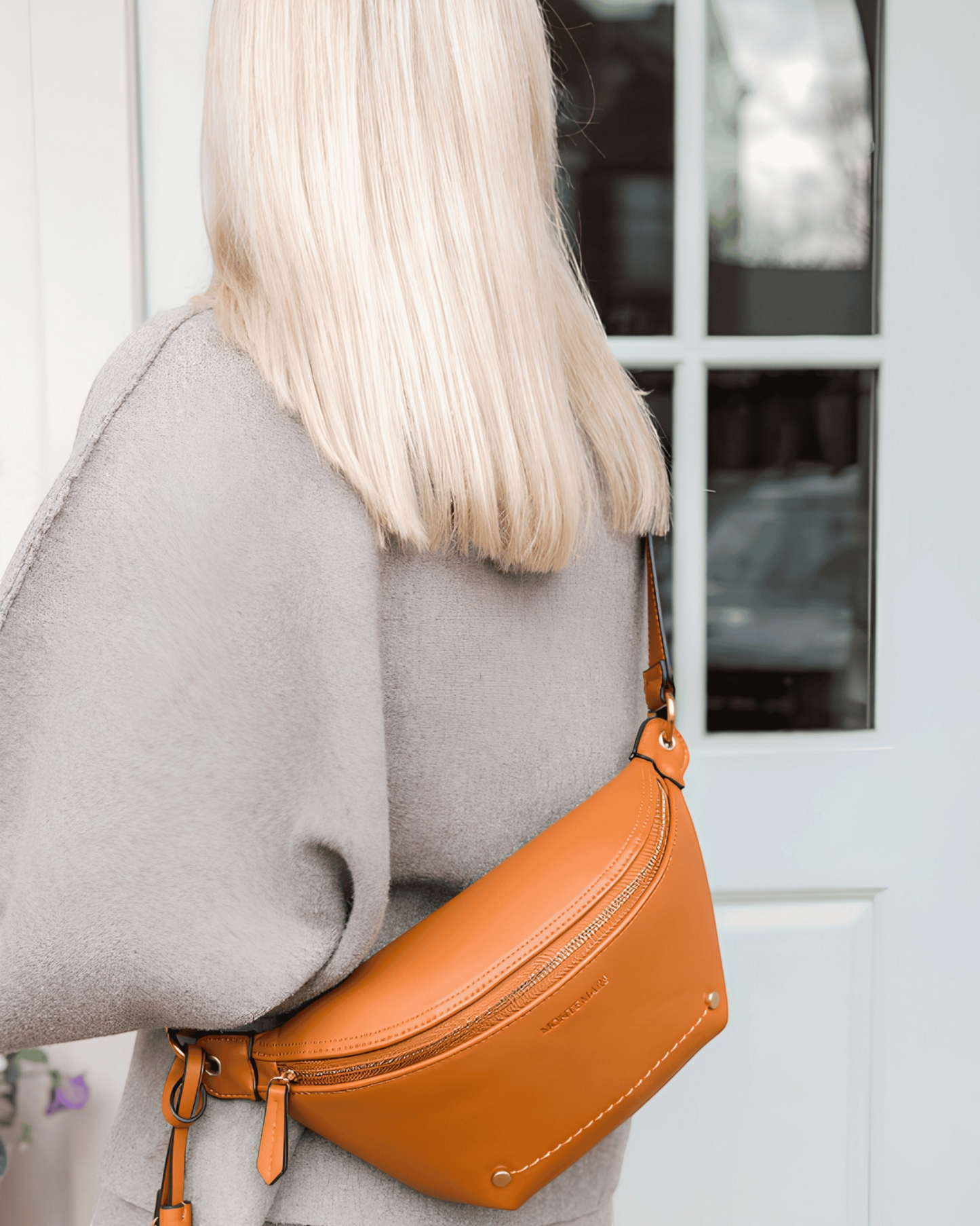 Montemaré Roma Sling bag in tan vegan leather worn as a crossbody, featuring a zip closure and signature tassel.
