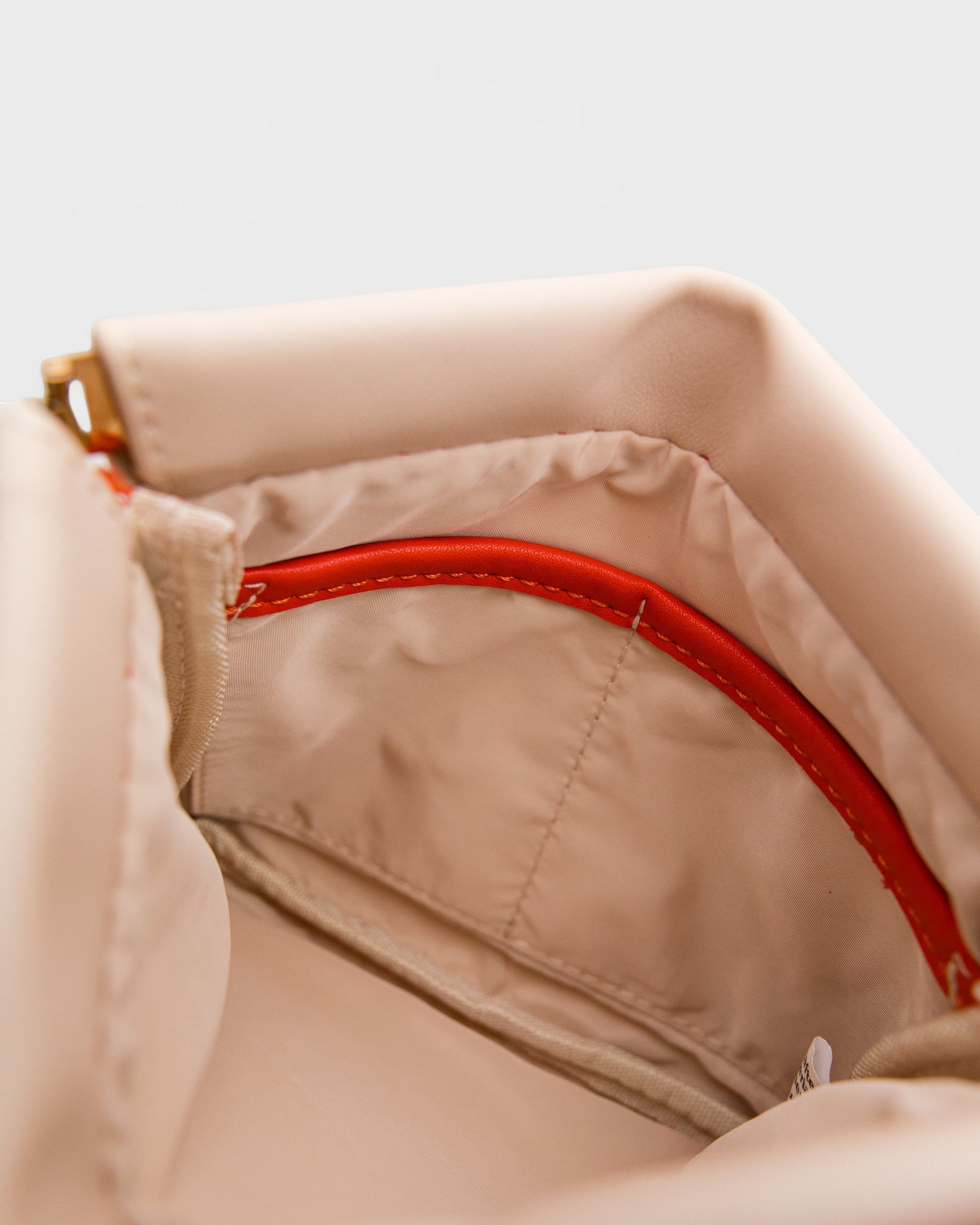 Interior of Montemaré Roma Square Pouch showing beige water-resistant lining, internal pocket, and red trim detail.