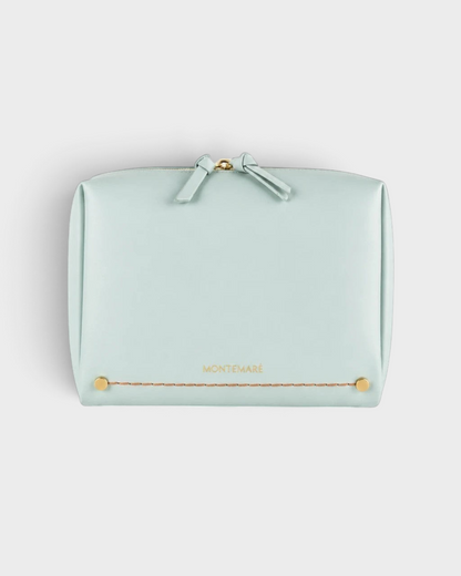 Montemaré Roma standing toiletry case in light blue vegan leather with gold hardware and a wide zipper opening.