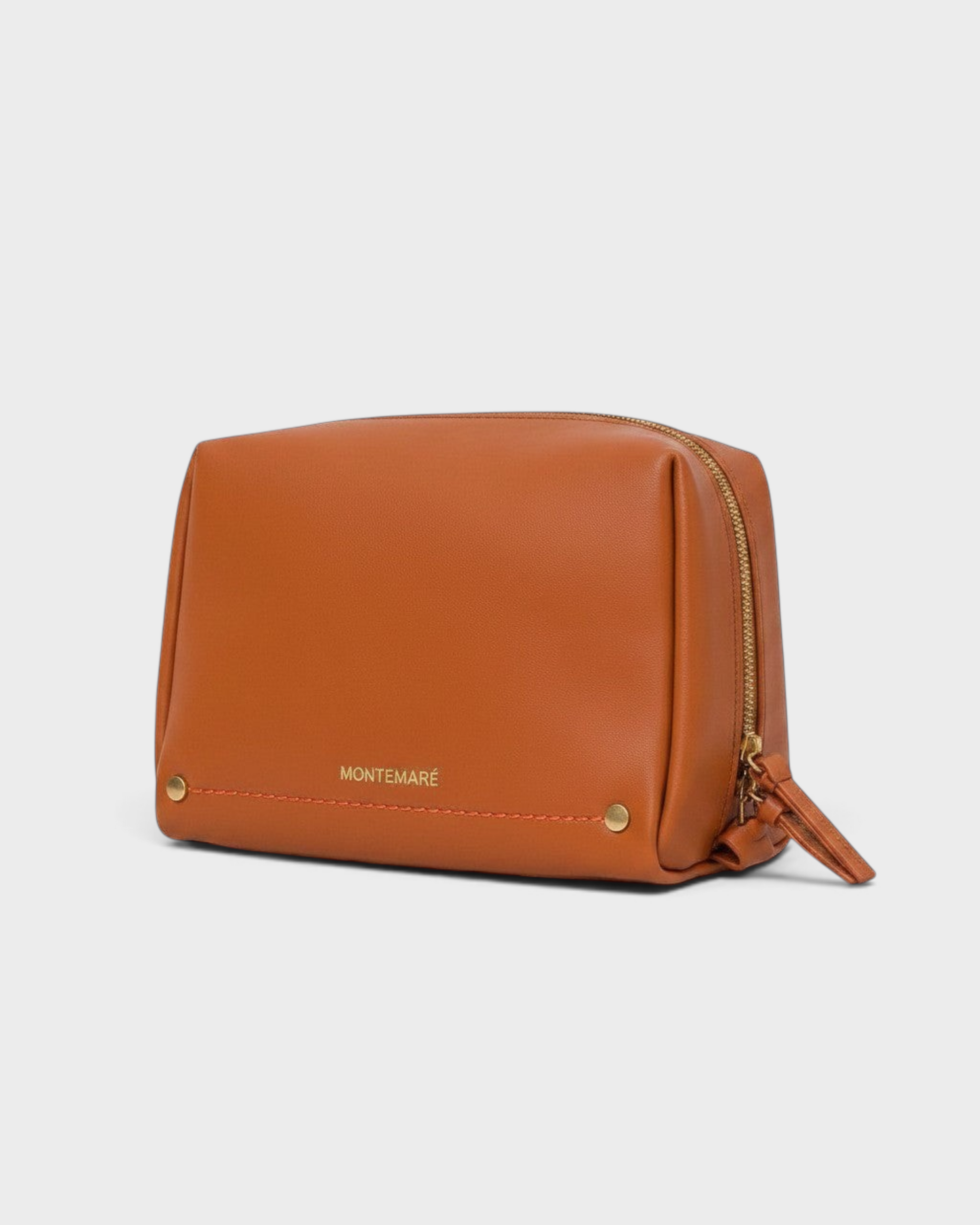 Montemaré Roma standing toiletry case in tan vegan leather with gold hardware and orange stitching details.