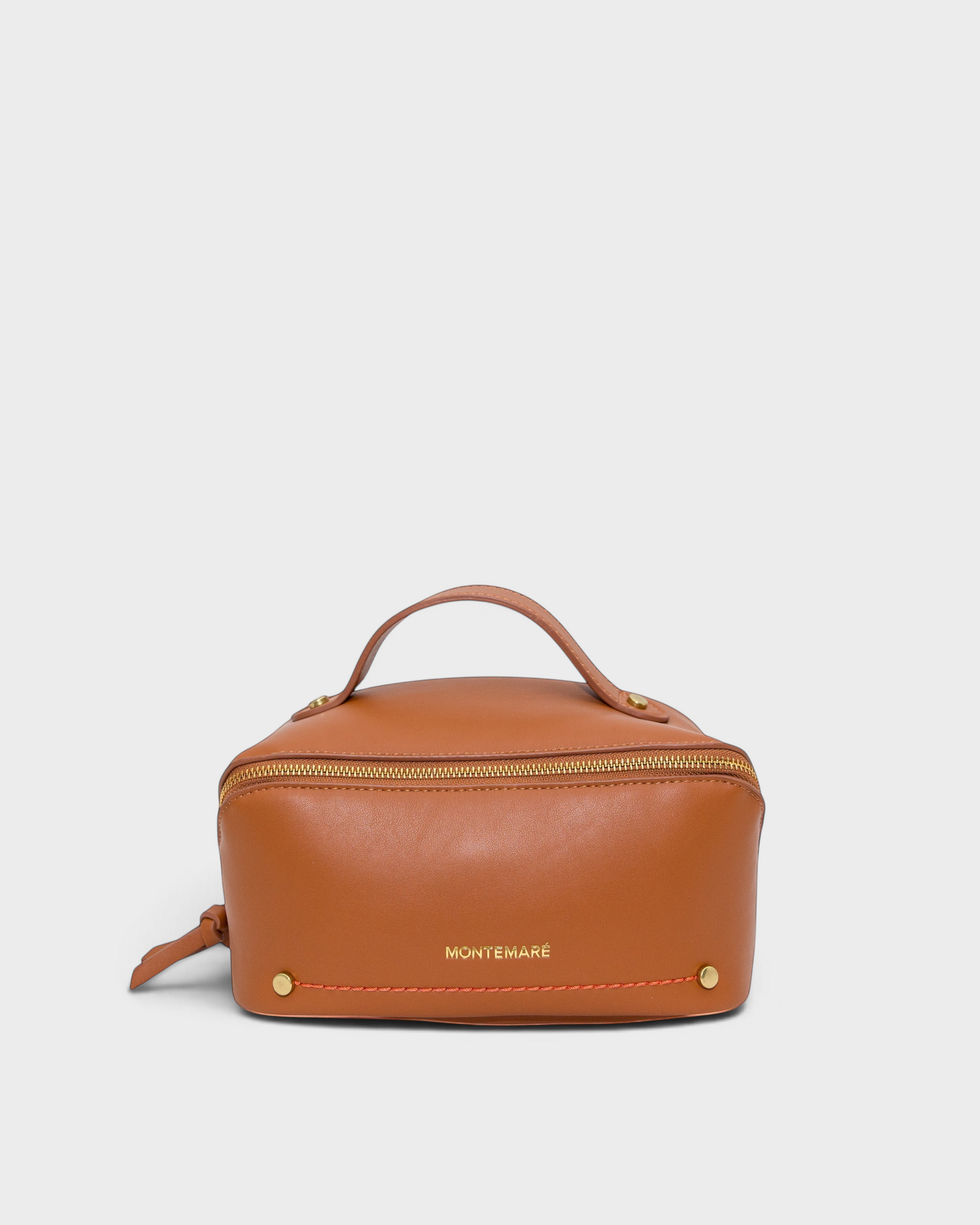 Montemaré Roma foldout toiletry case in tan vegan leather with a top handle, gold zipper, and orange accent stitching.