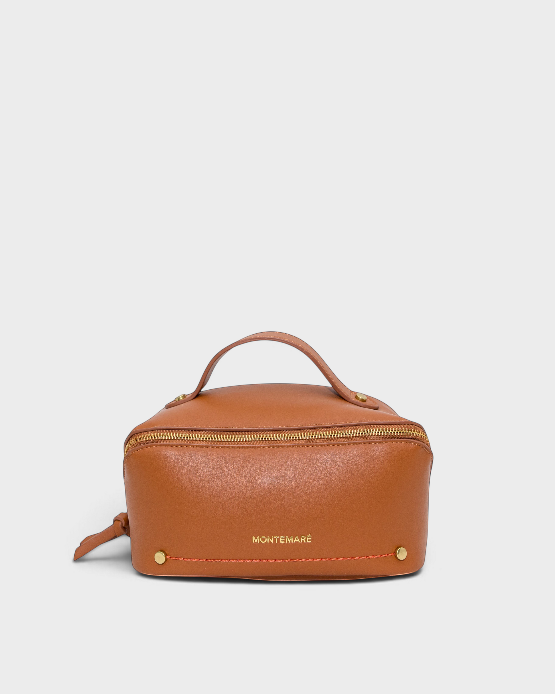 Montemaré Roma foldout toiletry case in tan vegan leather with a top handle, gold zipper, and orange accent stitching.