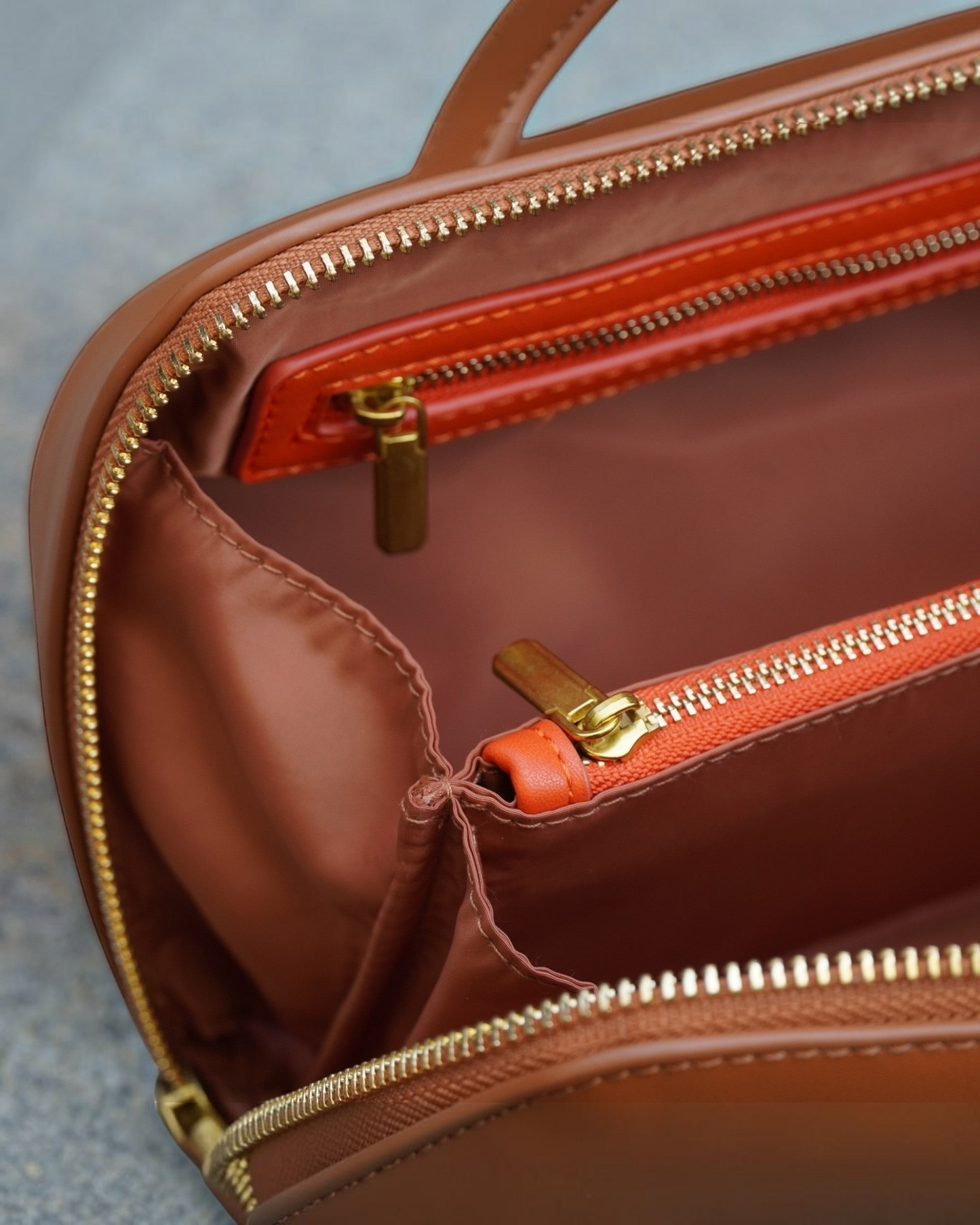 Montemaré Roma foldout toiletry case interior with brown lining, orange vegan leather accents, and gold zippers.
