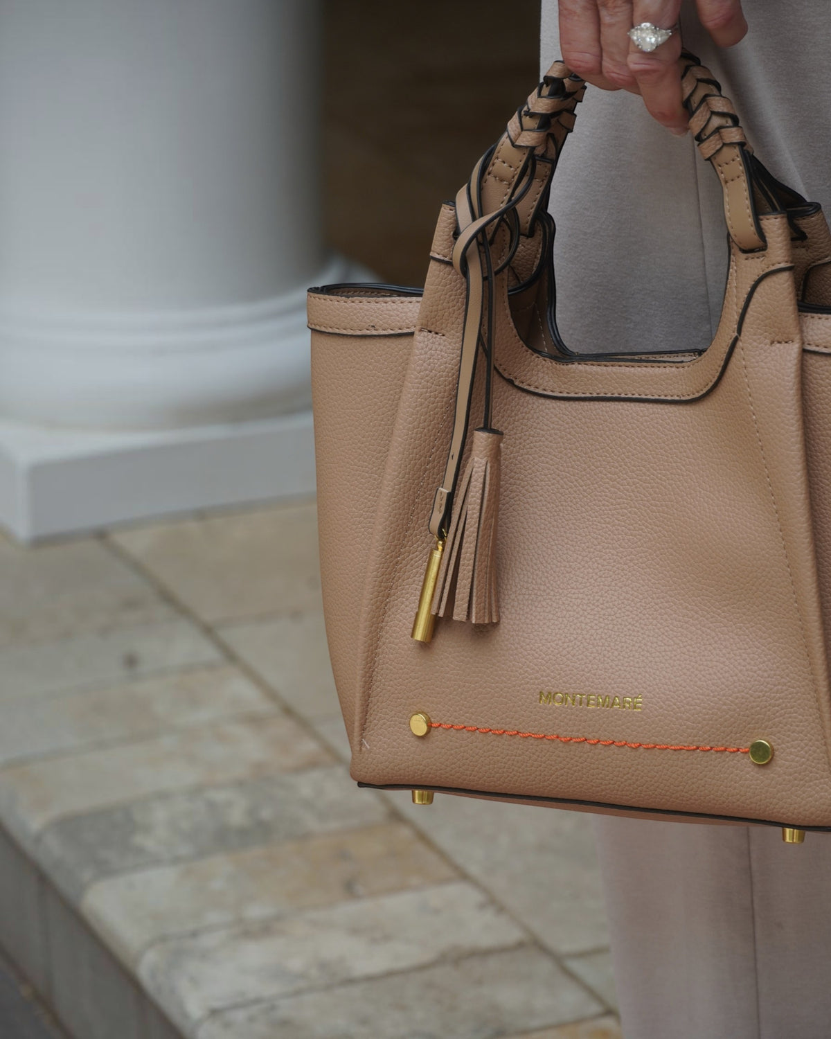 Montemaré Sedona crossbody bag in beige pebbled vegan leather with a braided handle and signature whistle tassel.