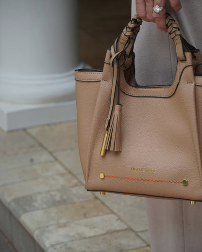 Montemaré Sedona crossbody bag in beige pebbled vegan leather with a braided handle and signature whistle tassel.