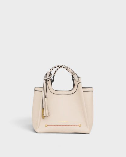 Montemaré Sedona crossbody bag in cream pebbled vegan leather with a braided top handle and signature whistle tassel.