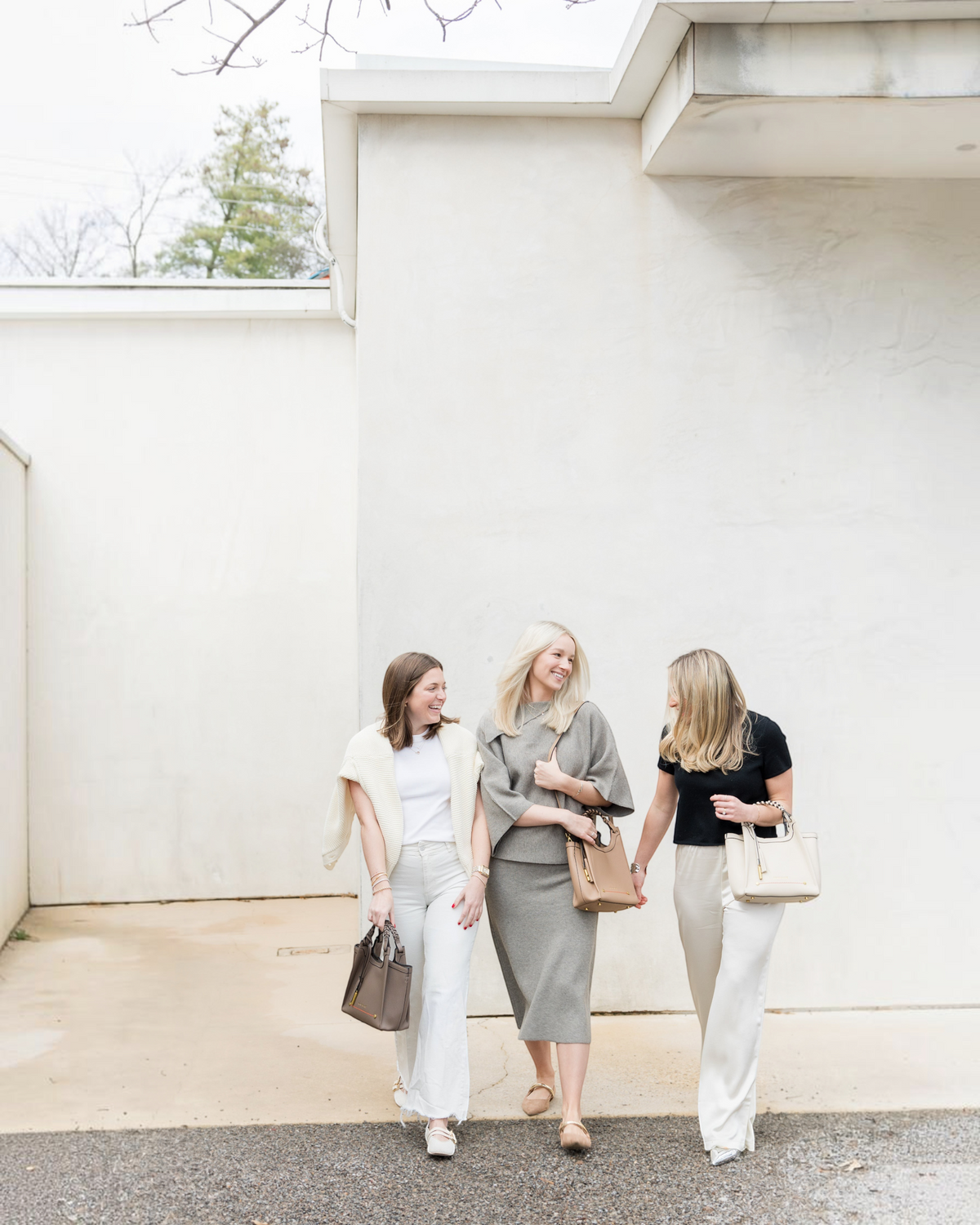 Three women walking outdoors carrying Montemaré Sedona Crossbody bags in neutral shades of taupe, beige, and cream.
