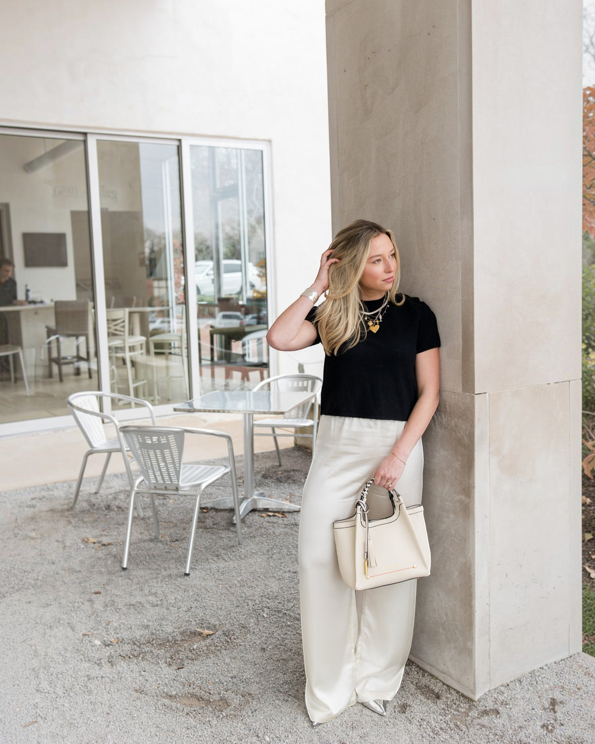Montemaré Sedona crossbody bag in cream vegan leather with braided handle and whistle tassel held by a woman
