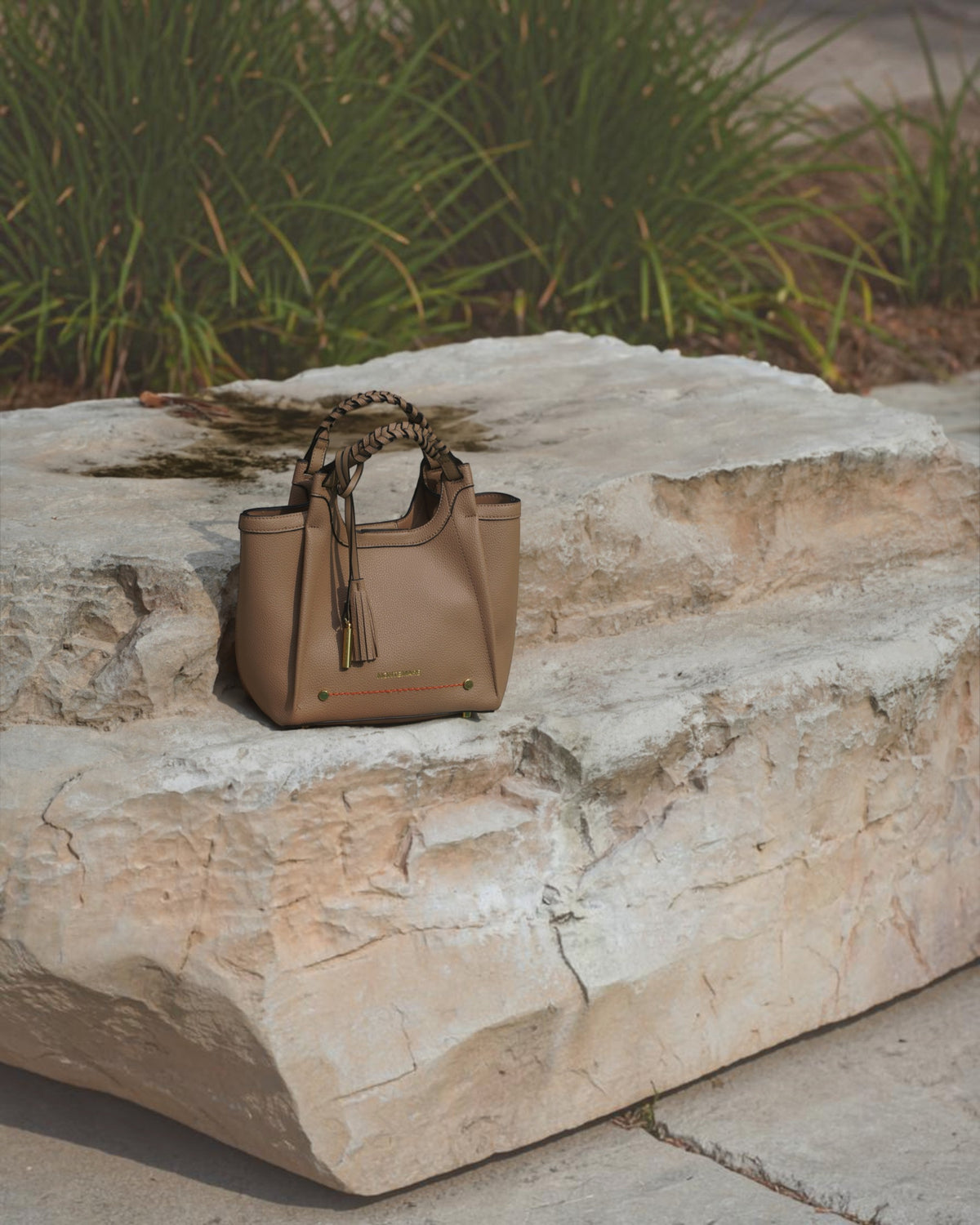 Montemaré Sedona crossbody bag in tan pebbled vegan leather with a braided handle and signature whistle tassel