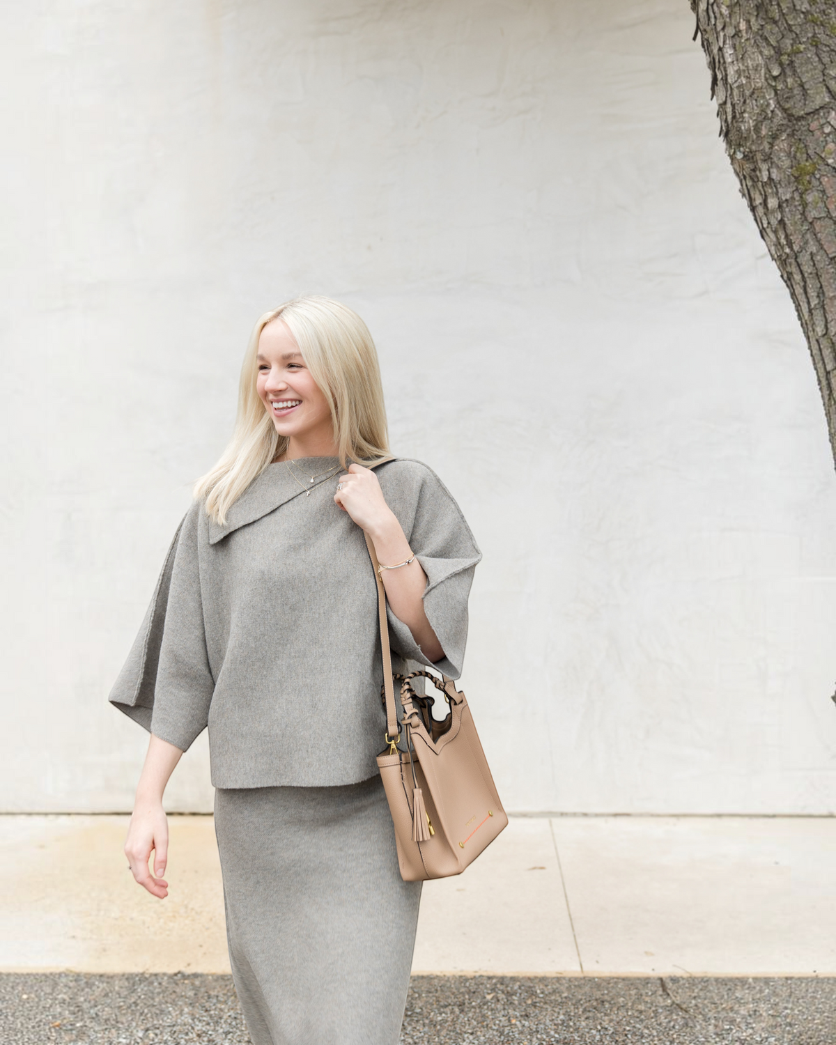 Montemaré Sedona Crossbody bag in tan vegan leather with braided handle and whistle tassel worn by a blonde woman