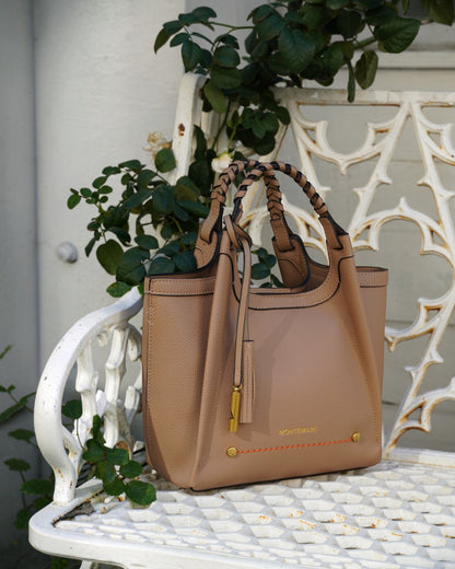 Montemaré Sedona crossbody bag in tan pebbled vegan leather with a braided handle and signature whistle tassel.