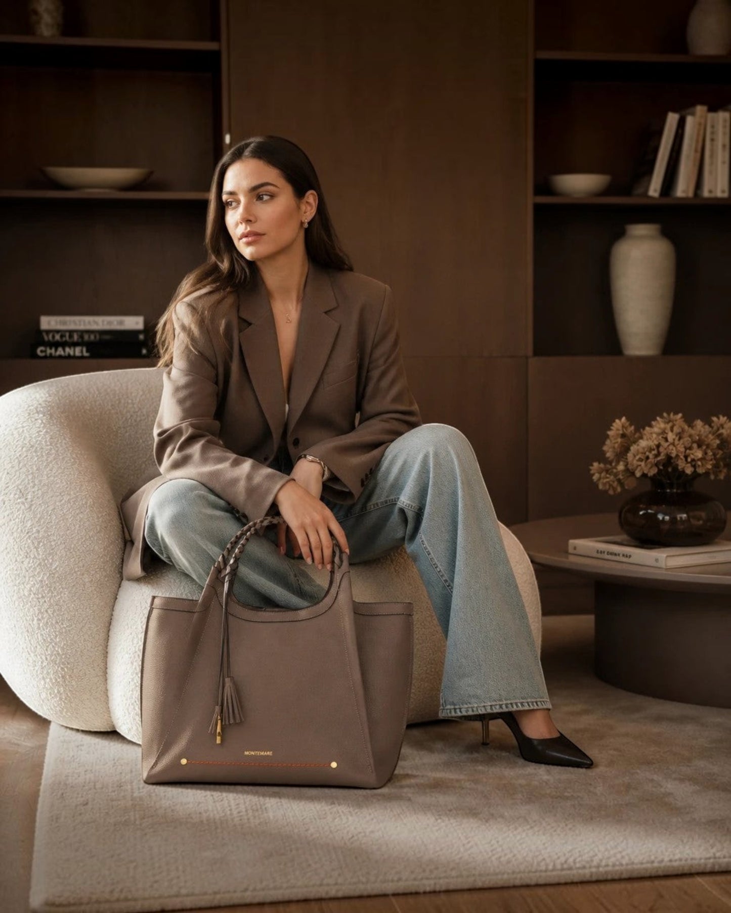 Woman sitting in a chair holding a Montemaré Sedona Work Tote in pebbled brown vegan leather with braided handles.