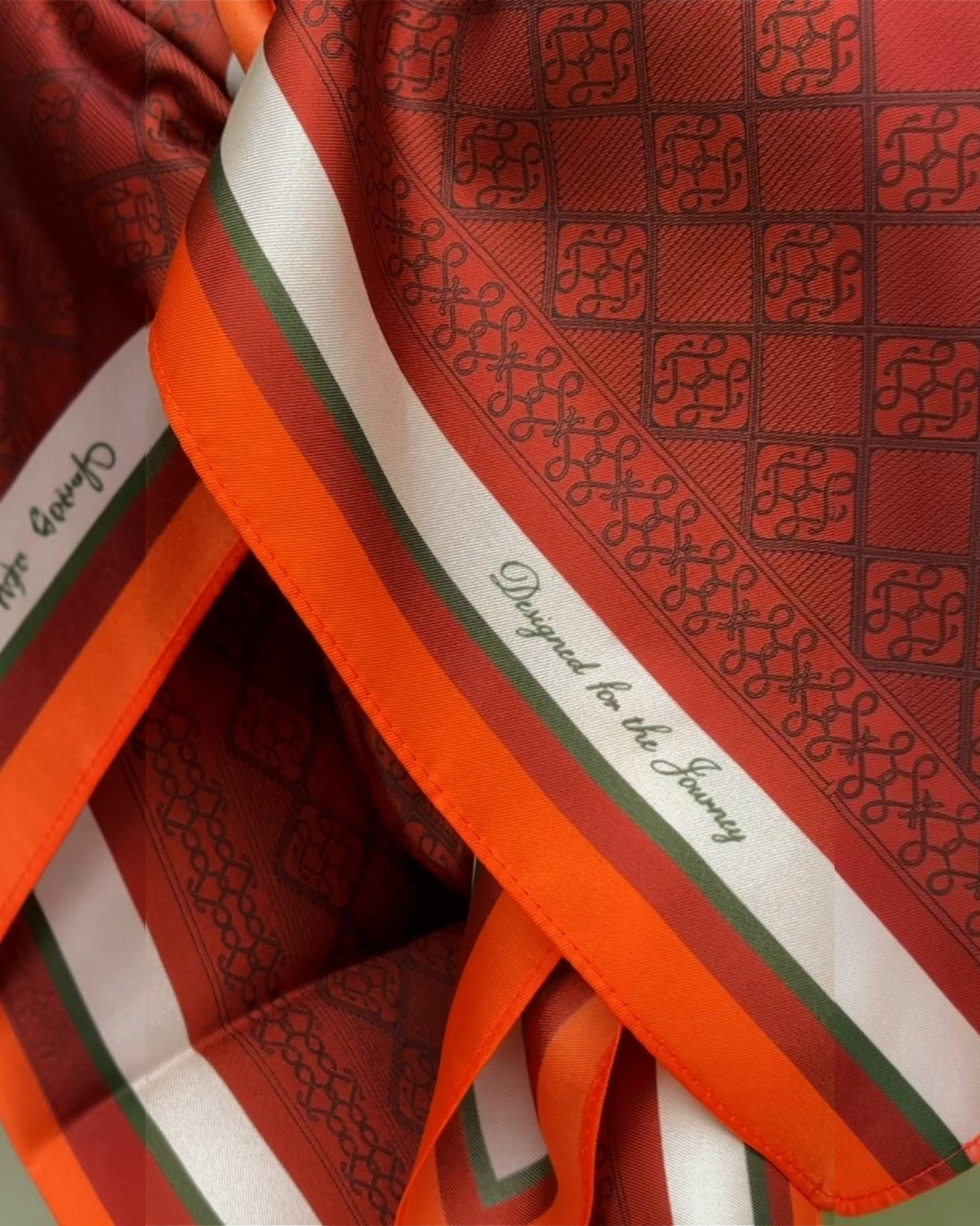 Montemaré silk square scarf featuring a signature grid pattern in orange, red, and green with a subtle sheen.