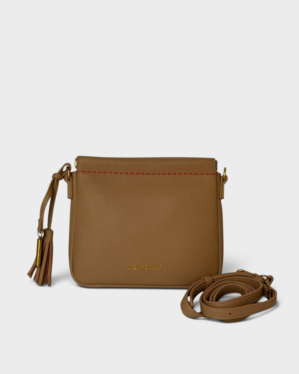 Montemaré square crossbody pouch in tan pebbled leather with a decorative tassel and red contrast stitching.