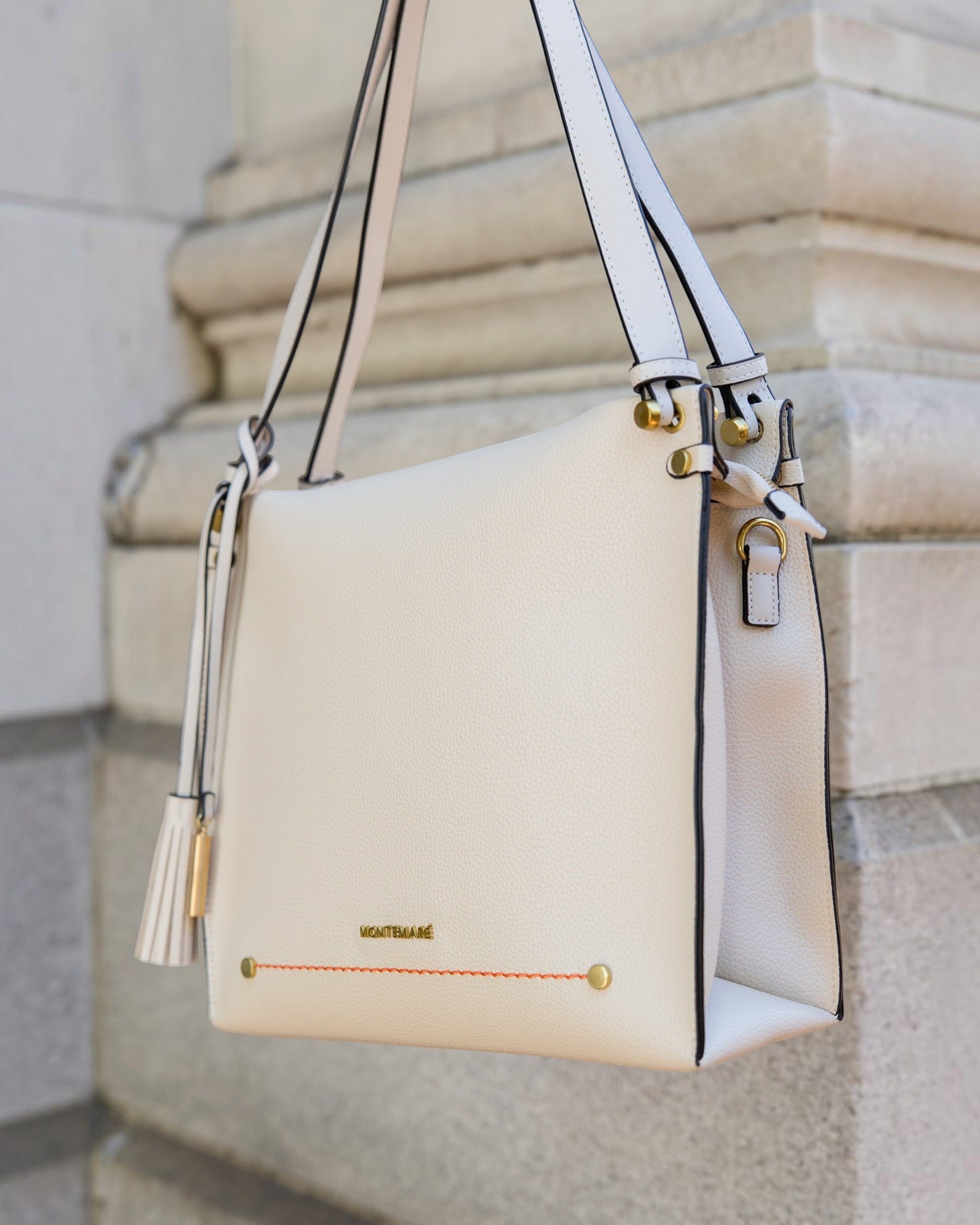 Montemaré Vienna shoulder bag in cream pebbled vegan leather with a signature safety whistle tassel and orange stitching.