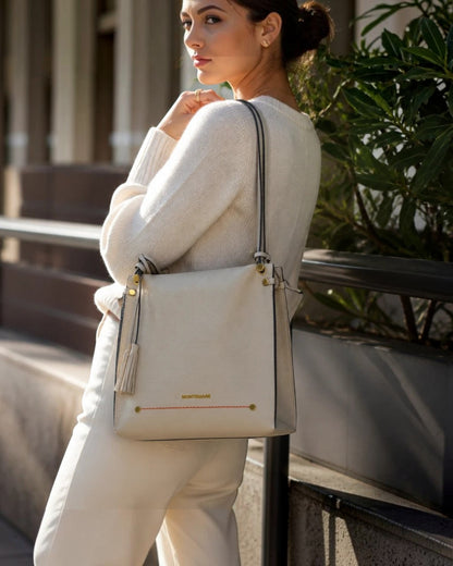 Montemaré Vienna shoulder bag in cream pebbled vegan leather with a signature whistle tassel worn by a woman